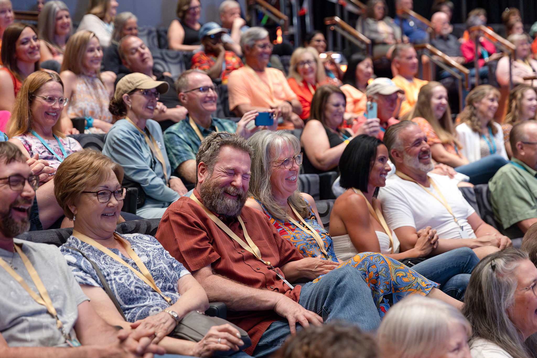 Audience members in various casual outfits smiling and laughing during a lively event.