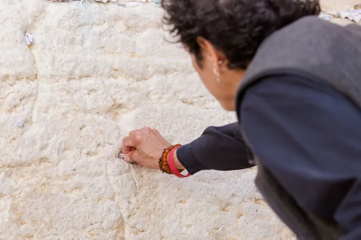 A woman placing a prayer note into the cracks of the Western Wall.