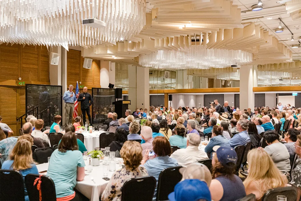 Conference room full of people sitting down, listening to the speaker on the stage