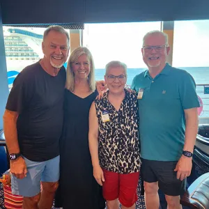 Group of four smiling travelers standing together on a cruise ship