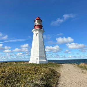 Tall white and red lighthouse with blue sky in the background